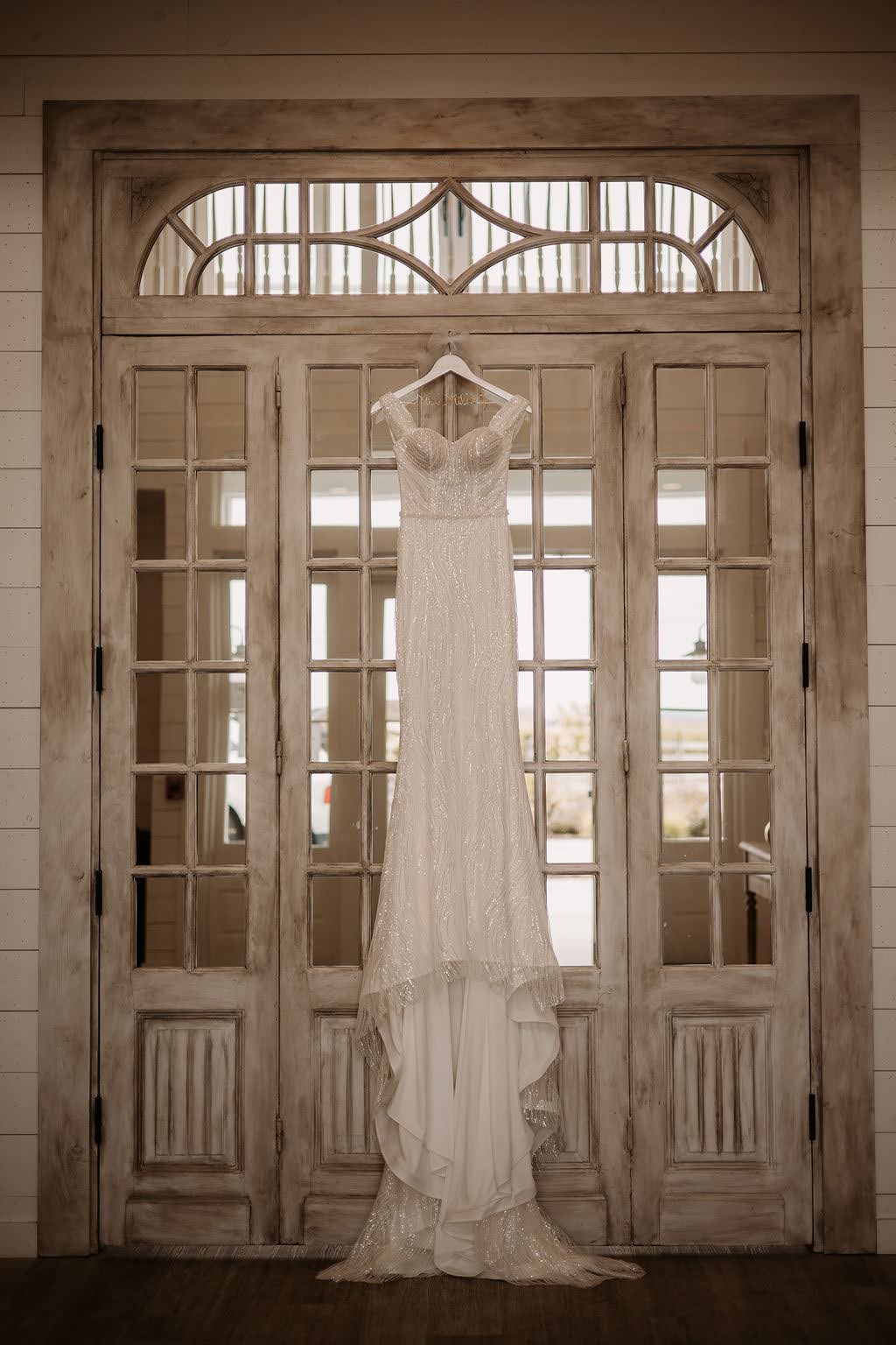 Sparkly wedding dress hanging on antique door at Providence Vineyard Wedding Venue