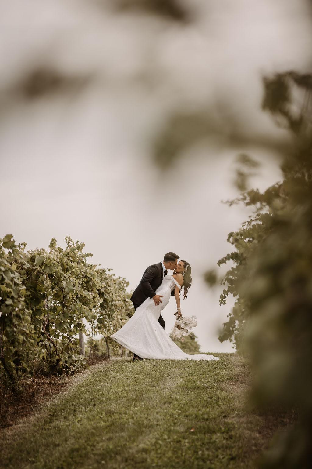 Bride and groom kissing through vines at wedding at Providence Vineyard wedding venue