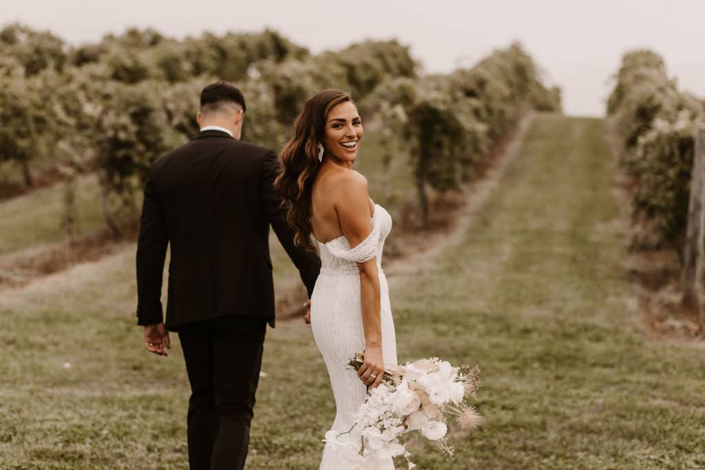 Bride and groom walking through vineyard at Providence Vineyard wedding venue