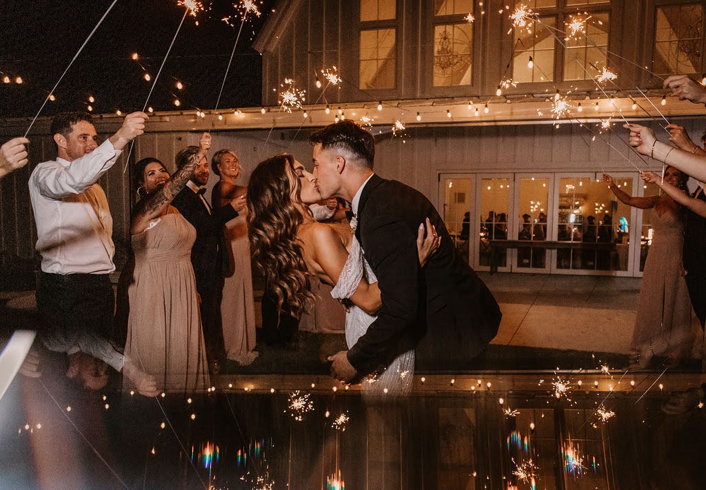 Bride and groom kissing sparkler exit outside white barn at Providence Vineyard wedding venue