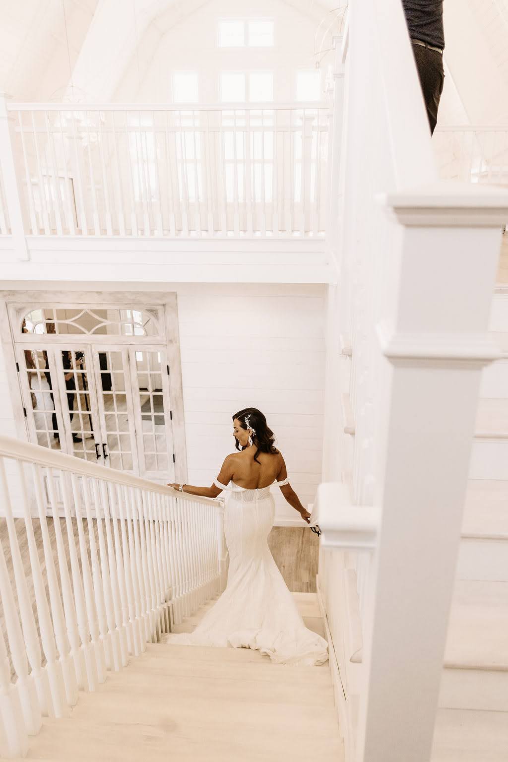 Bride walking down white staircase with antique glass door at Providence Vineyard wedding venue
