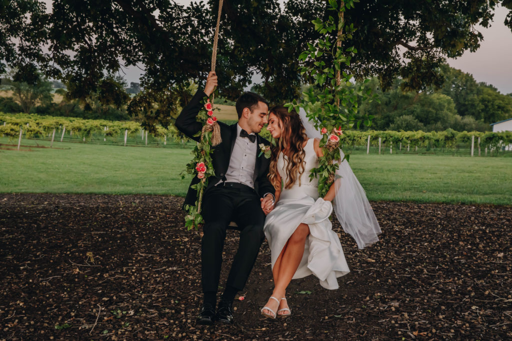 bride and groom on swing at oak tree with vineyard at wedding at Providence Vineyard Wedding Venue
