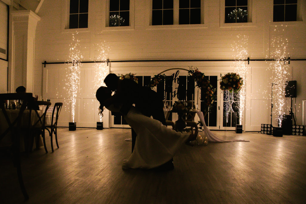 bride and groom dip kiss in front of lights reception at Providence Vineyard WEdding Venue