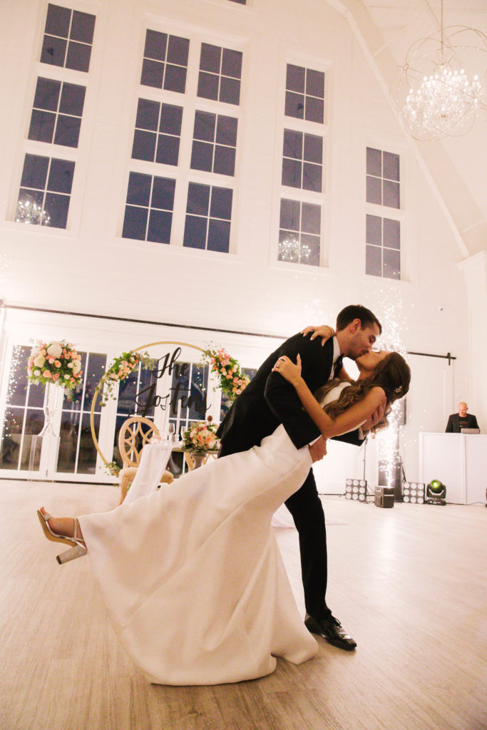 Bride and groom dip dance kiss window white barn at wedding at Providence Vineyard Wedding Venue