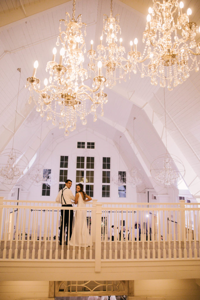 Bride and groom on balcony under chandeliers at Providence Vineyard wedding venue