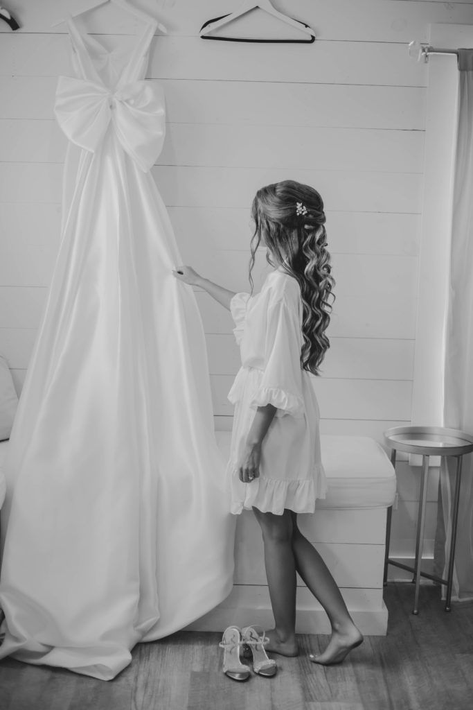 Bride in robe looking at wedding dress in bridal suite at Providence Vineyard wedding venue
